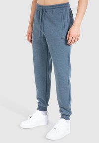 Blauwe sweatpants van zachte stof, met een elastische tailleband, zijzakken en geribde boorden, gecombineerd met witte sneakers.