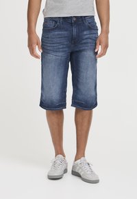 Pantalones cortos cargo de denim en azul oscuro con un acabado desgastado, que presentan bolsillos delanteros y traseros, y detalles de costura en los dobladillos.
