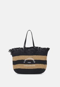 Czarna i beżowa torba na ramię w paski, z frędzlami, dwoma czarnymi skórzanymi uchwytami i białym haftowanym napisem z przodu.