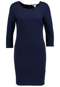 Robe bleu marine à longueur genoux avec une texture subtile en zigzag, col rond, manches trois-quarts, et fermeture éclair au dos.