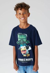 Marineblå bomulls-t-skjorte med et grafisk trykk av grønne og gule karakterer fra Minecraft, med teksten "A Minecraft Movie".