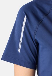 Marineblauw sportshirt met ademend, geperforeerd materiaal, korte mouwen en een witte logo-accent op de schouder.