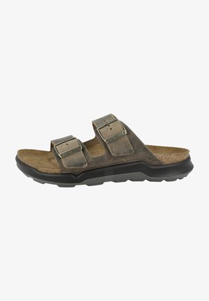 Brown leather sandals with two adjustable buckles, cork footbed, and a rugged black rubber outsole, featuring a textured surface.