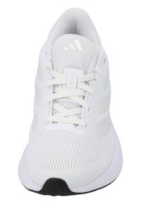 Baskets blanches de sport avec une tige en mesh, fermeture à lacets et trois bandes blanches discrètes sur les côtés. Semelle extérieure noire avec détail de logo.
