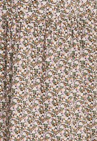 Kwiatowy materiał z małymi białymi, brązowymi, pomarańczowymi, lawendowymi i zielonymi kwiatami gęsto nadrukowanymi na beżowym tle z zebranym ściegiem.