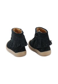 Botas de tobillo de ante negro con detalles de flecos, una superficie texturizada con brillos y una cremallera lateral, montadas sobre una suela de goma color beige.