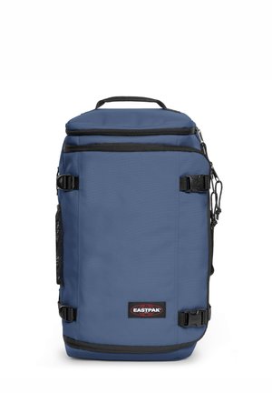 Mochila de tela azul con acentos negros, dos compartimentos con cremallera, bolsillo de malla lateral y asa superior. Incluye correas laterales ajustables.