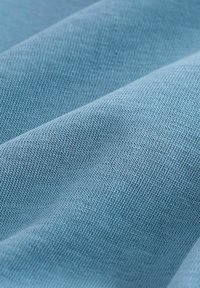 Svijetloplava tkanina s glatkom, teksturiranom površinom. Materijal ima dosljedan uzorak tkanja, ističući fine, ravne šavove.
