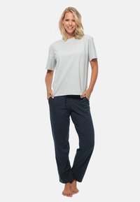 Grå bomullströja i kombination med mörkblå pyjamasbyxor som har vita prickar, rak passform och elastisk midja.