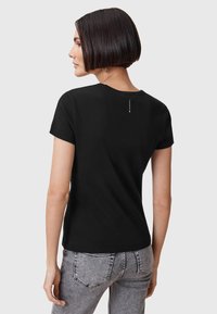 T-shirt nera realizzata in un tessuto morbido, con scollatura rotonda, maniche corte e un sottile dettaglio del logo sul retro.