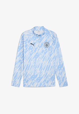 Camisa de manga larga azul claro con media cremallera, patrón abstracto diagonal, logo de Puma y el escudo del Manchester City en el pecho.
