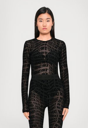 Body en maille noire à manches longues, avec un motif répétitif imprimé des mots "Versace" et "Couture" de différentes tailles. Design taille haute.