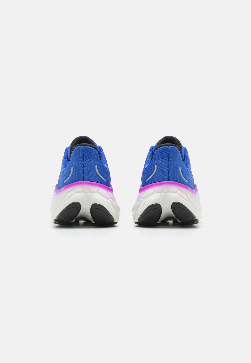 Par de zapatillas atléticas azules con suelas blancas y acentos rosados mostradas desde atrás sobre un fondo blanco liso.