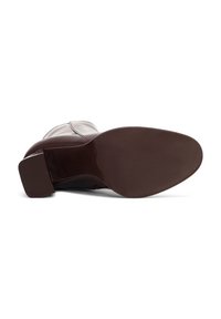 Stivale alla caviglia in pelle marrone con tacco quadrato, texture liscia e sottile dettaglio in cucitura rossa lungo le cuciture. Suola piatta con grip minimo.