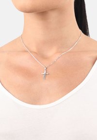 Silverfärgad kedjnehalsband som har ett enkelt kors-hänge. Hänget är platt med en polerad yta, och kedjan har en delikat design.