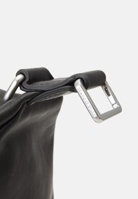 Black leather handbag strap featuring a silver metal buckle with "Marc O'Polo" engraved. Soft texture with a relaxed design.
