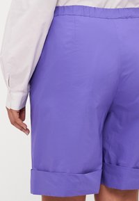 Pantaloni corti viola realizzati in un tessuto liscio, con una vestibilità comoda, vita elastica e risvolti all'orlo.