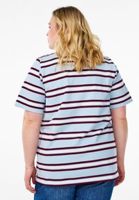 T-shirt rayé présentant des bandes horizontales bleues, bordeaux et blanches. Manches courtes, encolure ronde, fabriqué à partir d'un tissu doux et texturé.