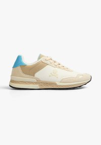 Beige and cream sneaker with a blue accent, featuring a skull logo, textured panels, and a patterned sole. Lace-up design.