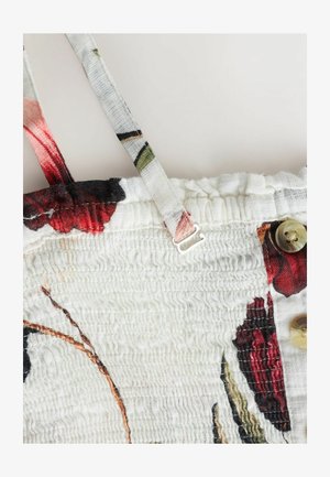 Tkanina w kwiatowy wzór z czerwonymi i zielonymi akcentami na białym tle. Posiada regulowane ramiączka oraz mały detal z mosiężnym guzikiem.