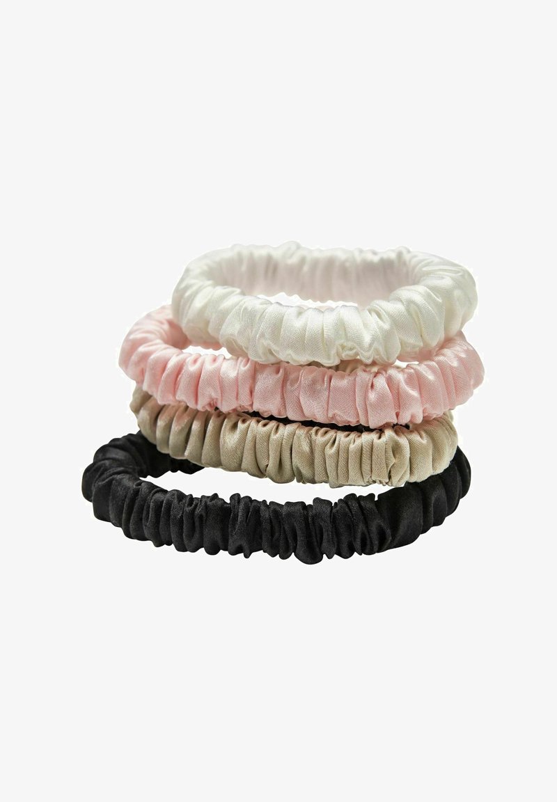 Pile de quatre chouchous en satin froncé en blanc, rose, beige et noir sur fond blanc.