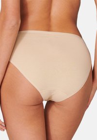 Mutande beige in cotone a vita alta con una texture liscia, dotate di una cintura elastica e cuciture minime per garantire comfort e una vestibilità senza soluzione di continuità.