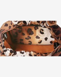 Interno di una borsa tote con stampa leopardata marrone e bianca, caratterizzato da una texture liscia, con foderatura in tessuto e design con apertura arricciata.