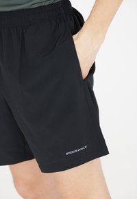 Mustat urheiluhousut, jotka on valmistettu kevyestä kankaasta. Niissä on joustava vyötärönauha, sivutaskut ja valkoinen "ENDURANCE"-logo.