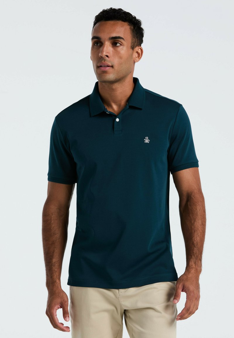 Polo shirt teal foncé à manches courtes et col, avec un petit logo brodé sur la poitrine gauche, fabriqué en tissu lisse.
