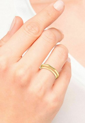 Goldfarbener Ring mit einem glatten, abgerundeten Design und zwei ineinander verschlungenen Bändern. Die Oberfläche hat eine polierte Finish, die das Licht subtil reflektiert.