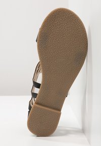 Svart sandal med flera remmar, strukturerad gummisul och rund tå. Innersulan har markering för storlek 37.