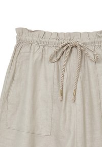 Shorts en lin beige avec une taille élastique, un cordon de serrage ajustable et deux poches avant. Texture subtile et matériau léger.