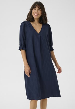 Abito blu navy con scollatura a V, maniche a tre quarti a sbuffo e dettagli arricciati ai polsini, realizzato in un tessuto testurizzato con righe verticali.