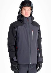 Giacca da sci impermeabile da uomo di colore grigio scuro con dettagli neri, tasche con cerniera e cappuccio, completata da guanti neri e casco.