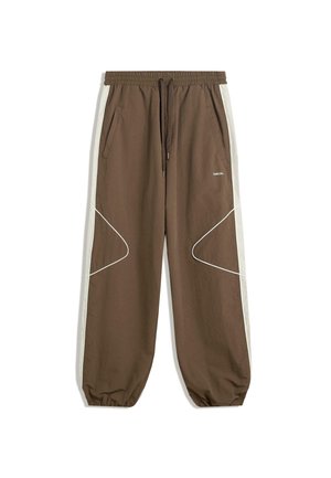 Brown joggers with a drawstring waistband, side pockets, and contrasting cream side panels featuring white stitching and curved patterns.
