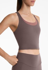 Lila sportcrop-top med rund halsringning och breda axelband. Passformen är formsydd och den har ett kontrasterande rosa innerlager.
