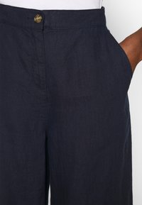 Mörkblå linnebyxor med framknäppning, sidofickor och ett slätt, strukturerat tyg med avslappnad passform.