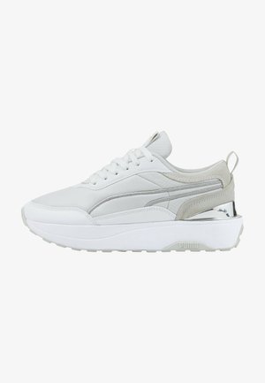 Sneaker Puma bianca e grigia con design stringato, suola ammortizzata e accento metallico sul tallone, mostrata di lato su uno sfondo bianco.