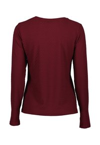 Langsleeve top in bordeaux met een gestructureerd chevronpatroon. Heeft een ronde halslijn en een getailleerde pasvorm.