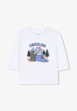 T-shirt bianca a maniche lunghe con stampa grafica raffigurante un orso che pesca, montagne e alberi, con il testo "TIMBERLAND" sopra.