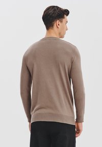 Brązowy sweter dzianinowy z długimi rękawami, okrągłym dekoltem, prążkowanym dołem i mankietami. Gładka tekstura, dopasowany krój i gładki tylny widok.