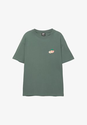 Zelené bavlnené tričko s voľným strihom, s malým vyšívaným motívom broskyne a listu na hrudi. Krátke rukávy a okrúhly výstrih.