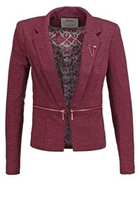Blazer bordeaux pour femme avec des détails de fermeture éclair en or rose à la taille, une doublure intérieure à motifs et une épingle décorative sur le revers gauche.