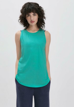 Ein ärmelloses, rundhalsiges Tanktop in lebhaftem Teal, mit einer glatten Textur und lockerer Passform, kombiniert mit dunklen, flauschigen Schlafanzügen.