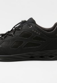 Černá sportovní obuv s texturovaným svrškem a výřezovými panely, kulatou špičkou a gumovou podrážkou s akcenty v diamantovém vzoru.