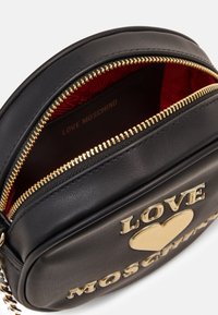 Borsa a tracolla in ecopelle nera con finiture dorate, con dettagli in "LOVE" e cuori. Fodera interna rossa e chiusura con zip.