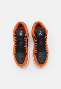 Baskets de sport noires et orange avec dessus en cuir, embout perforé, semelle en caoutchouc et lacets noirs ornés d'un logo blanc.