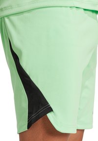 Helle mintgrüne Sportshorts mit einem schwarzen Seitenpaneel. Hergestellt aus glattem, dehnbarem Stoff; verfügt über einen gesteppter Saum und seitliche Schlitze.