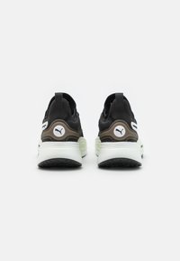 Černé a šedé sportovní boty s texturovaným svrškem, silnou bílou mezipodešví a výrazným logem na patě. Akcenty v olivově zelené.