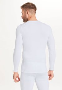 Witte lange mouwen atletische shirt met een getailleerd ontwerp, gladde textuur en naadloze constructie, geschikt voor sportkleding.